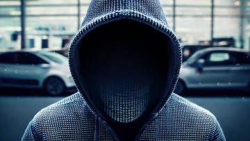 Symbolhafte Darstellung eines Cyberkriminellen vor einem Autohaus