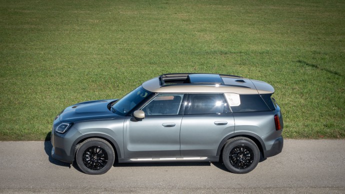 Mini Countryman D (U25) Mini Countryman Diesel in der Ausstattungslinie Favoured in 3. Generation in der Seitenansicht leicht von oben mit geöffnetem Schiebedach.